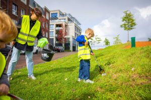 Een team van Wijkhelden raapt met een knijper en emmer in de aanslag werfafval op uit de natuur
